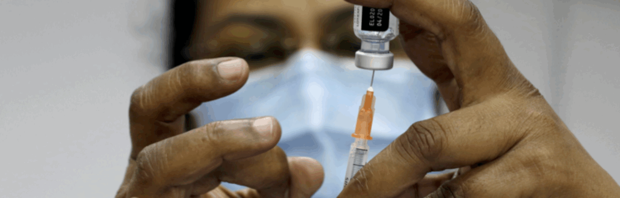A nurse prepares a dose of vaccine for injection.