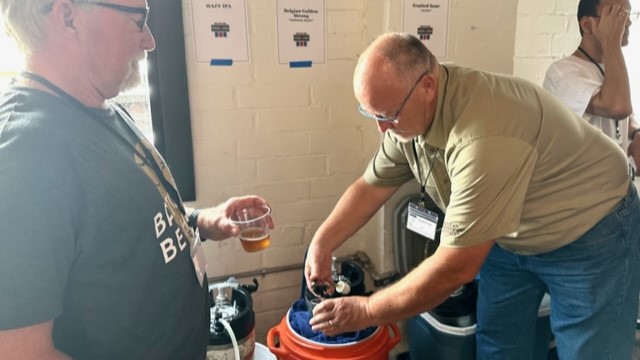 Mike Lentz, left, and Randall Merideth ull beers at the “Joes versus Pros” competition between established breweries and home brewers. | Michelle Corum, Jacksonville Today