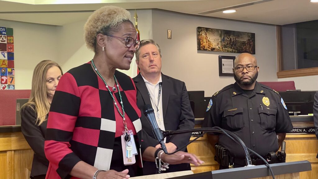 A woman at a podium in a school board meeting room.