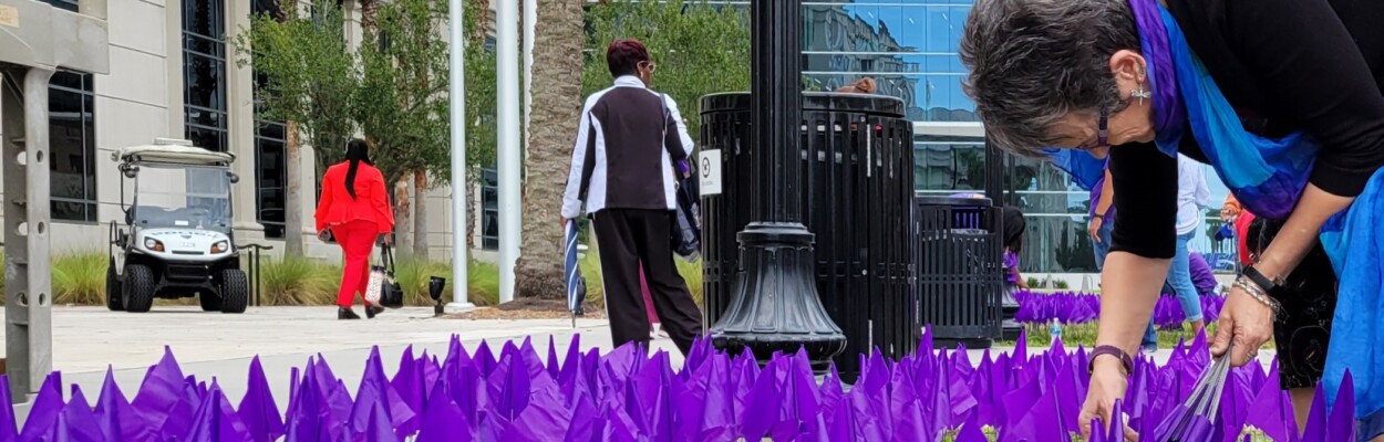 Hubbard House CEO Gail Patin plants a row of purple flags in front of the Duval County Courthouse on Friday, Sept. 29, 2023. Each flag represents a victim of domestic abuse who filed an injunction against their abuser.