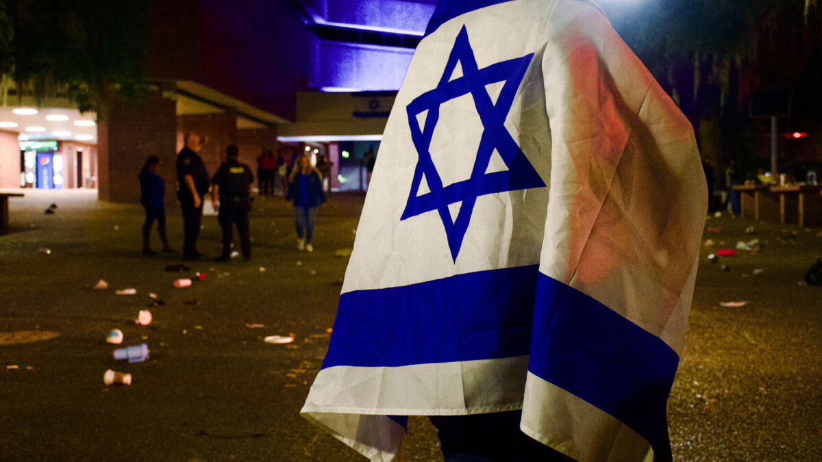 An unidentified University of Florida student wraps himself in an Israeli flag during a campus vigil Oct. 9, 2023, for victims of Hamas attacks. | Augustus Hoff, WUFT News