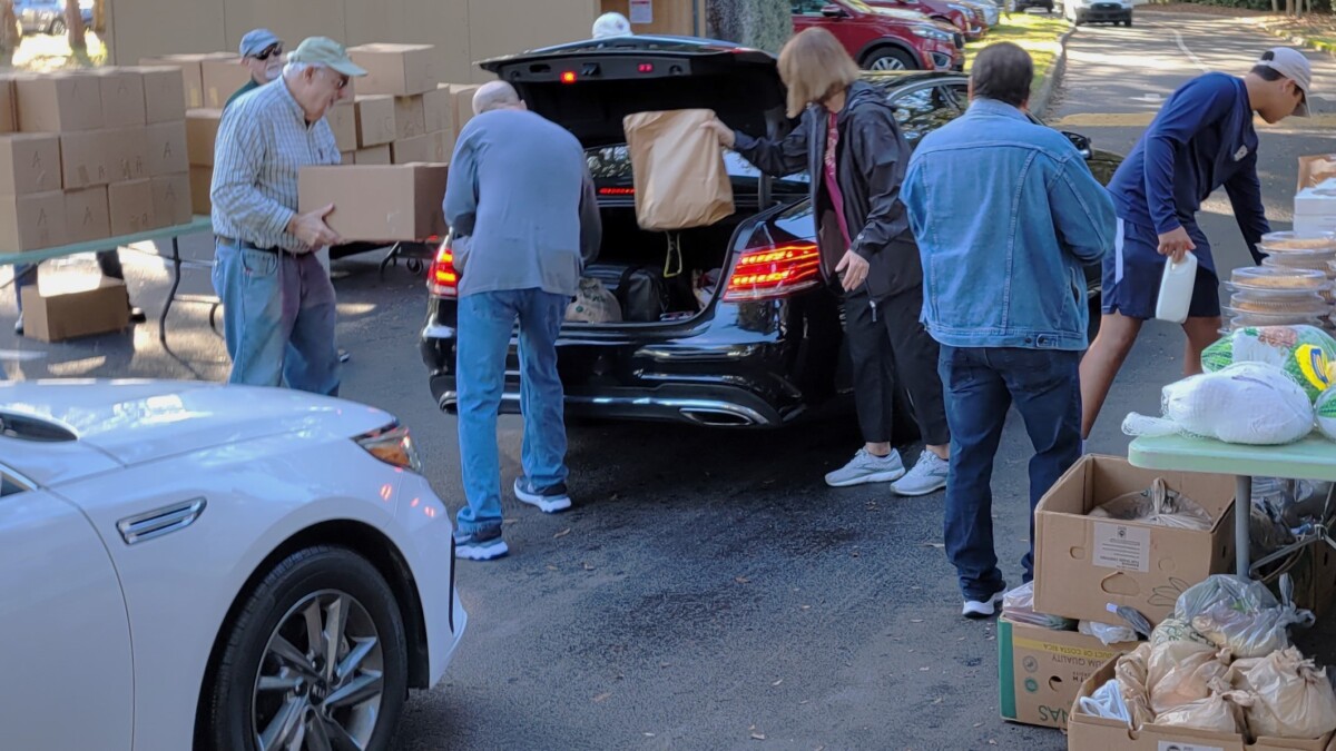Volunteers from the Mandarin Rotary Club and elsewhere load up a Thanksgiving meal to one of about 400 families who came for its 33rd annual holiday food program. | Dan Scanlan, WJCT News 89.9