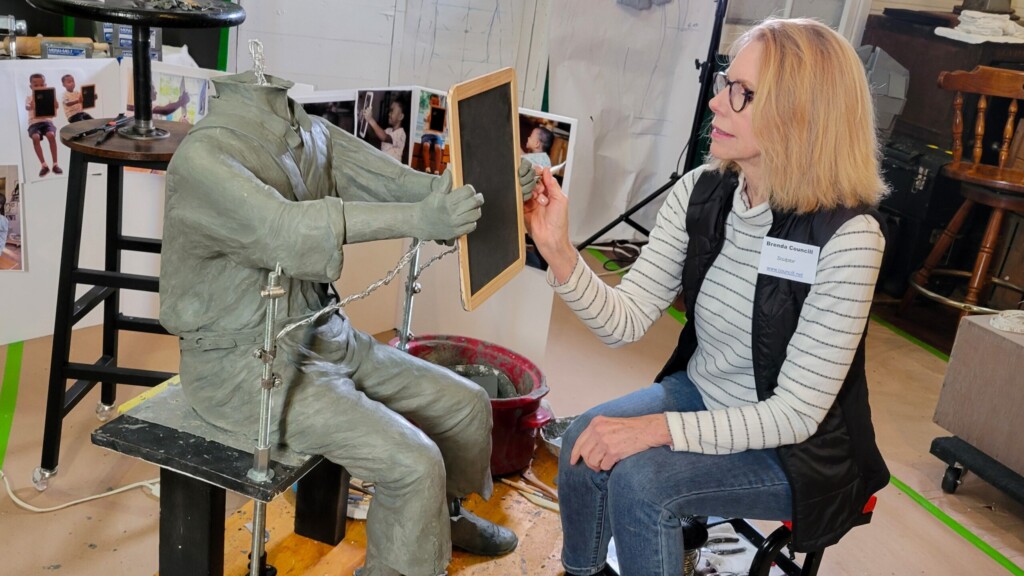 Artist Brenda Councill works on the hands of a clay sculpture of a farm boy, part of a life-size bronze statue she is doing of Harriet Beecher stowe for a Mandarin park. | Dan Scanlan, WJCT News 89.9