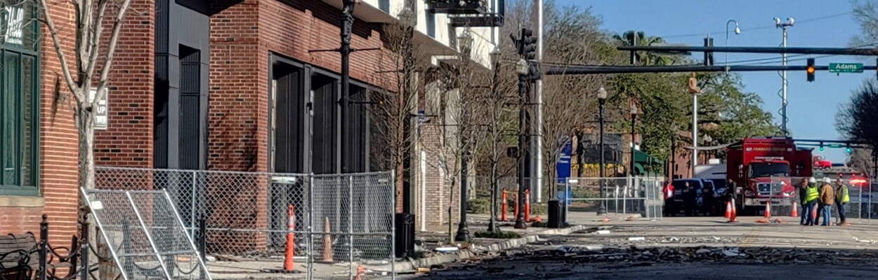 Safety fencing goes up on Wednesday around the Rise Doro apartment building as the city prepares to demolish most of it after a fire gutted the structure. | Dan Scanlan, WJCT News 89.9