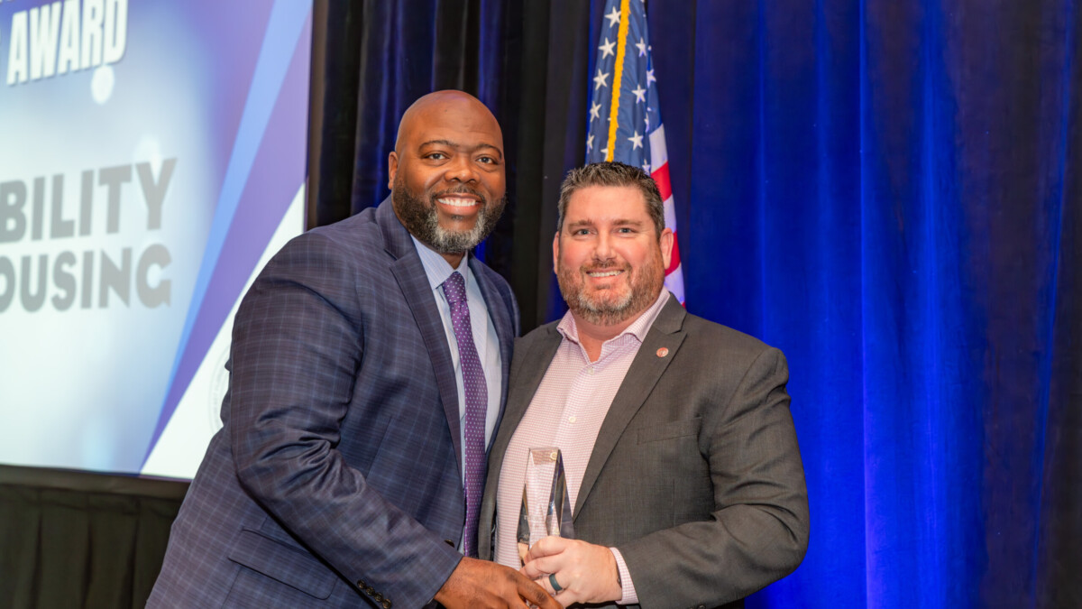 Reggie Fullwood of Ability Housing's board of directors, left, accepts the Bill Soforenko Affordable Housing Award from Northeast Florida Builders Association Board member Zach Scott with Ameris Bank. | Ability Housing