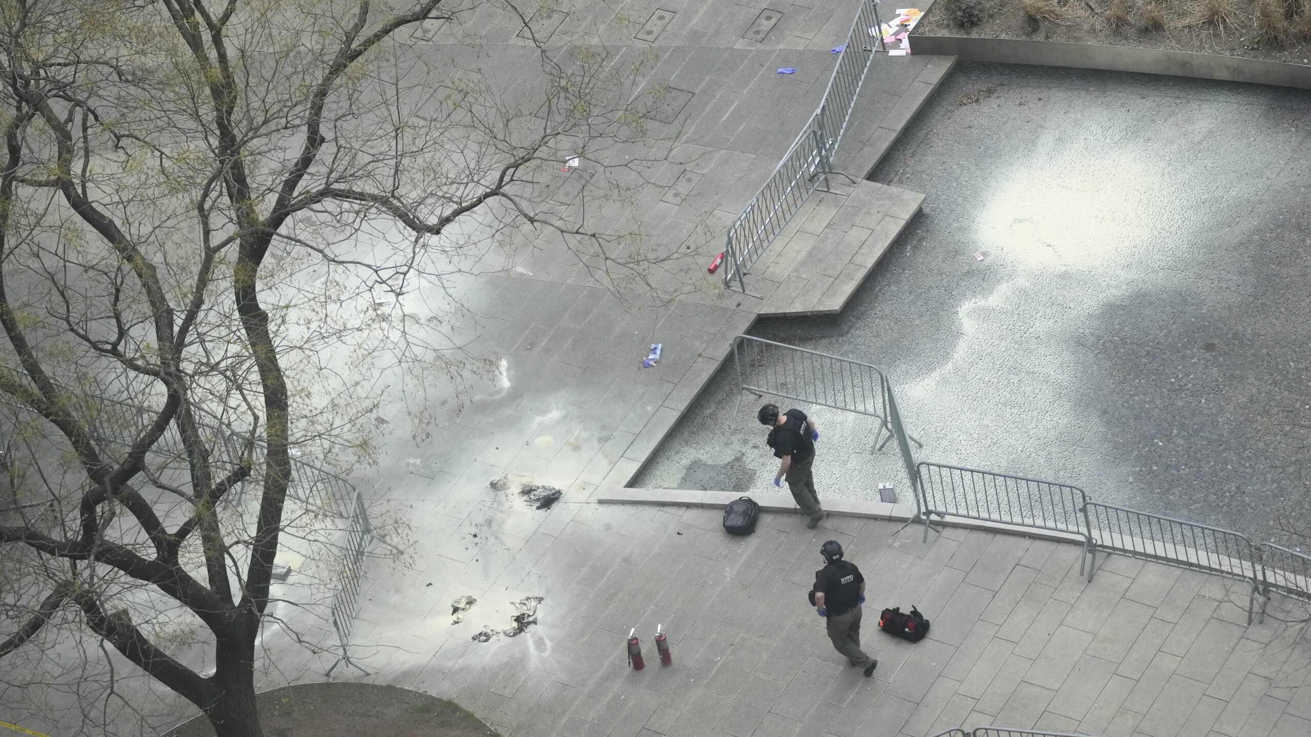 New York police officers inspect a backpack left at the scene where a man lit himself on fire in a park on Friday, April 19, 2024. | Mary Altaffer, AP
