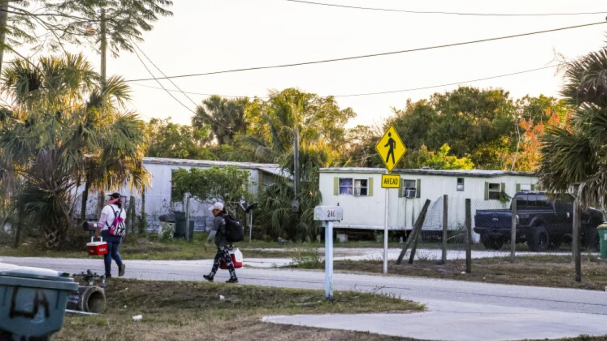 A couple of farmworkers walk home in Immokalee after Hurricane Irma struck the small town in 2017. | Andrea Melendez, WGCU