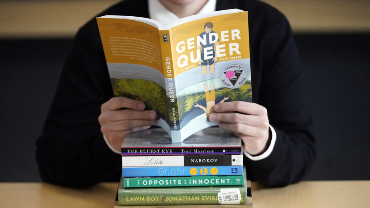 Amanda Darrow, director of youth, family and education programs at the Utah Pride Center, poses with books that have been the subject of complaints from parents on Dec. 16, 2021, in Salt Lake City. | Rick Bowmer, AP