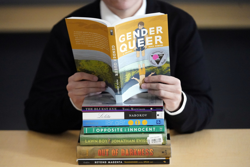 Amanda Darrow, director of youth, family and education programs at the Utah Pride Center, poses with books that have been the subject of complaints from parents on Dec. 16, 2021, in Salt Lake City. | Rick Bowmer, AP