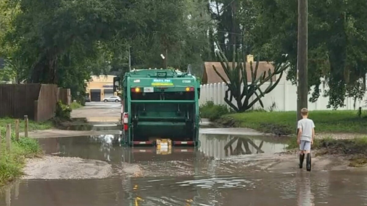 A garbage truck plows through a flooded road in the city's Sans Pareil neighborhood. | News4Jax