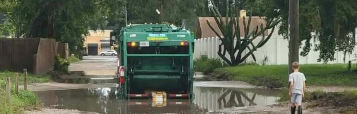 A garbage truck plows through a flooded road in the city's Sans Pareil neighborhood. | News4Jax