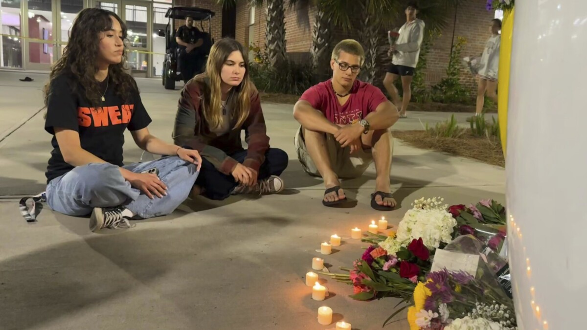 Students sitting at a makeshift memorial at FSU.