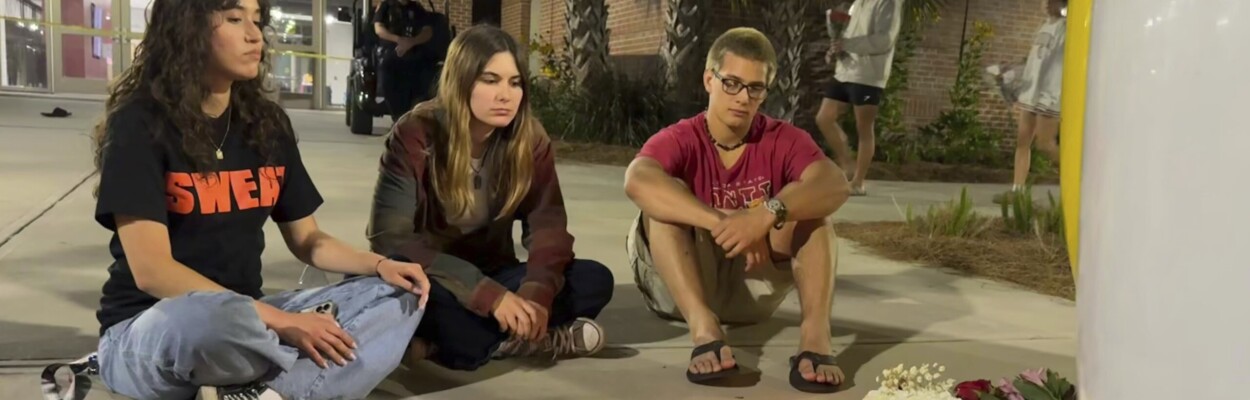Students sitting at a makeshift memorial at FSU.