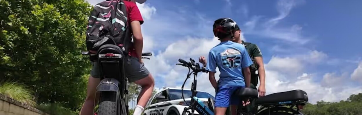 A police officer talks to children on e-bikes.
