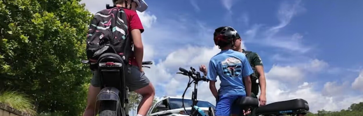 A police officer talks to children on e-bikes.
