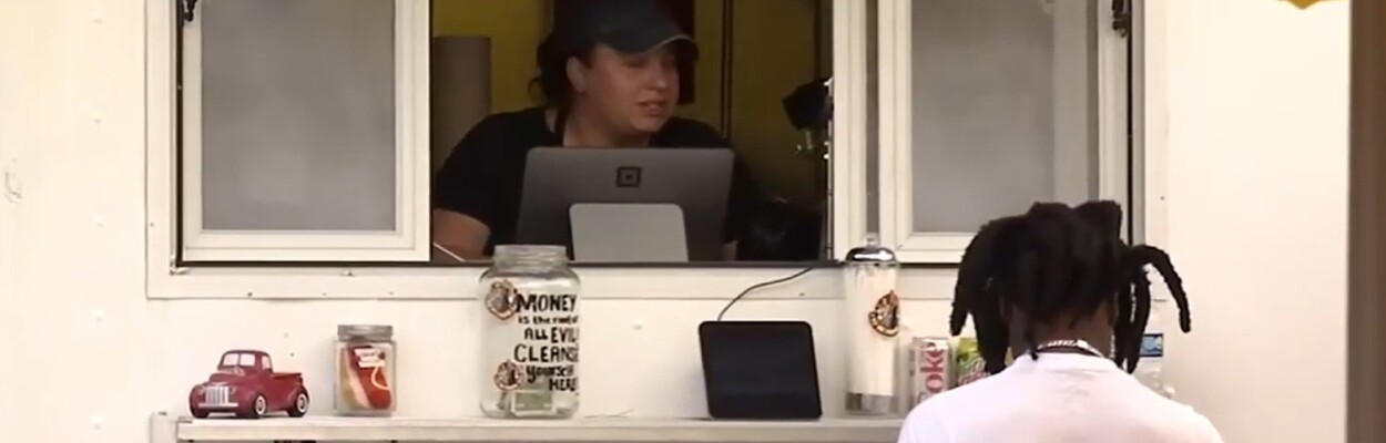 A young person gets service at a food truck window.