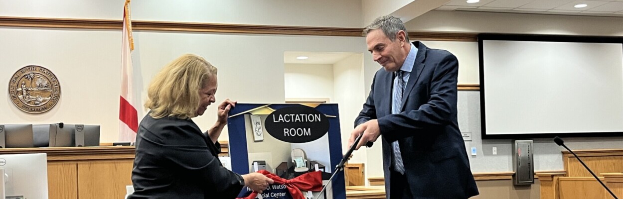 Ingrid Osborn, president of the St. Johns Association for Women Lawyers, and Circuit Judge Howard Maltz cut the ceremonial ribbon on a space for nursing and taking care of babies in the St. Johns County Courthouse