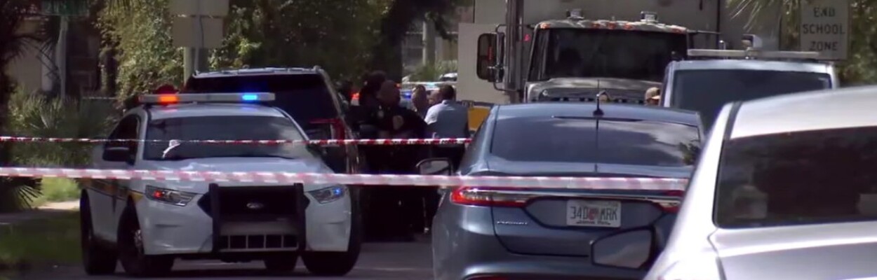 Police cars block a street where a man was shot to death