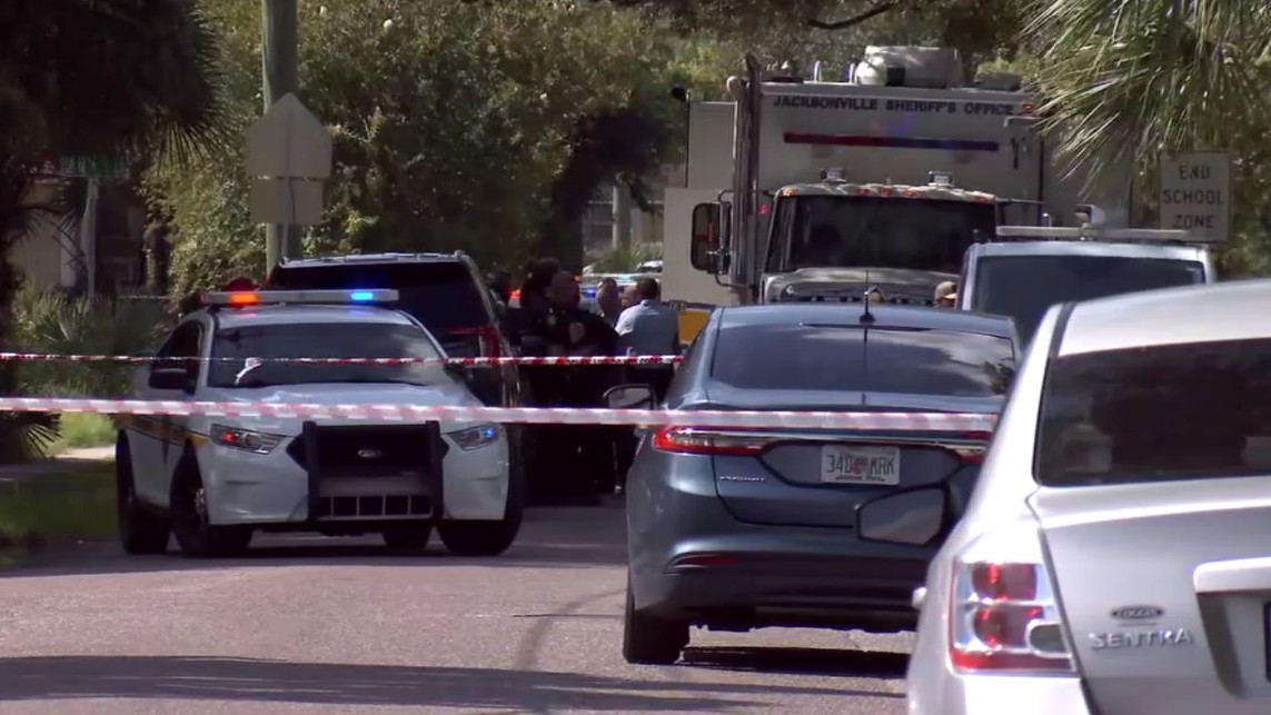Police cars block a street where a man was shot to death