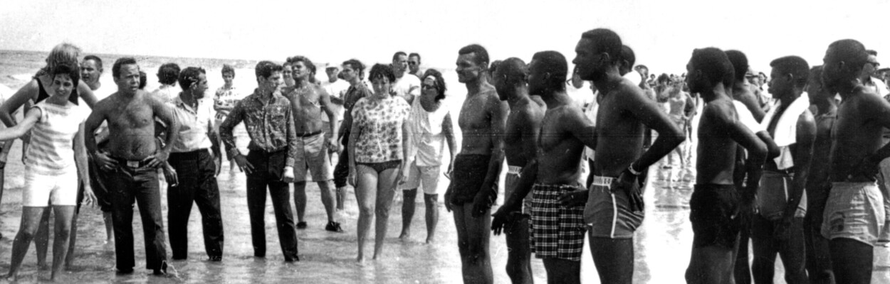 A historical photo of Black people and white people facing off on the beach in St. Johns County