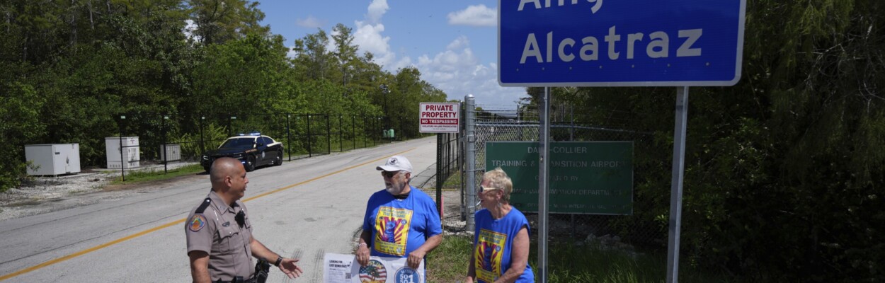 Protesters with police officer outside Alligator Alcatraz