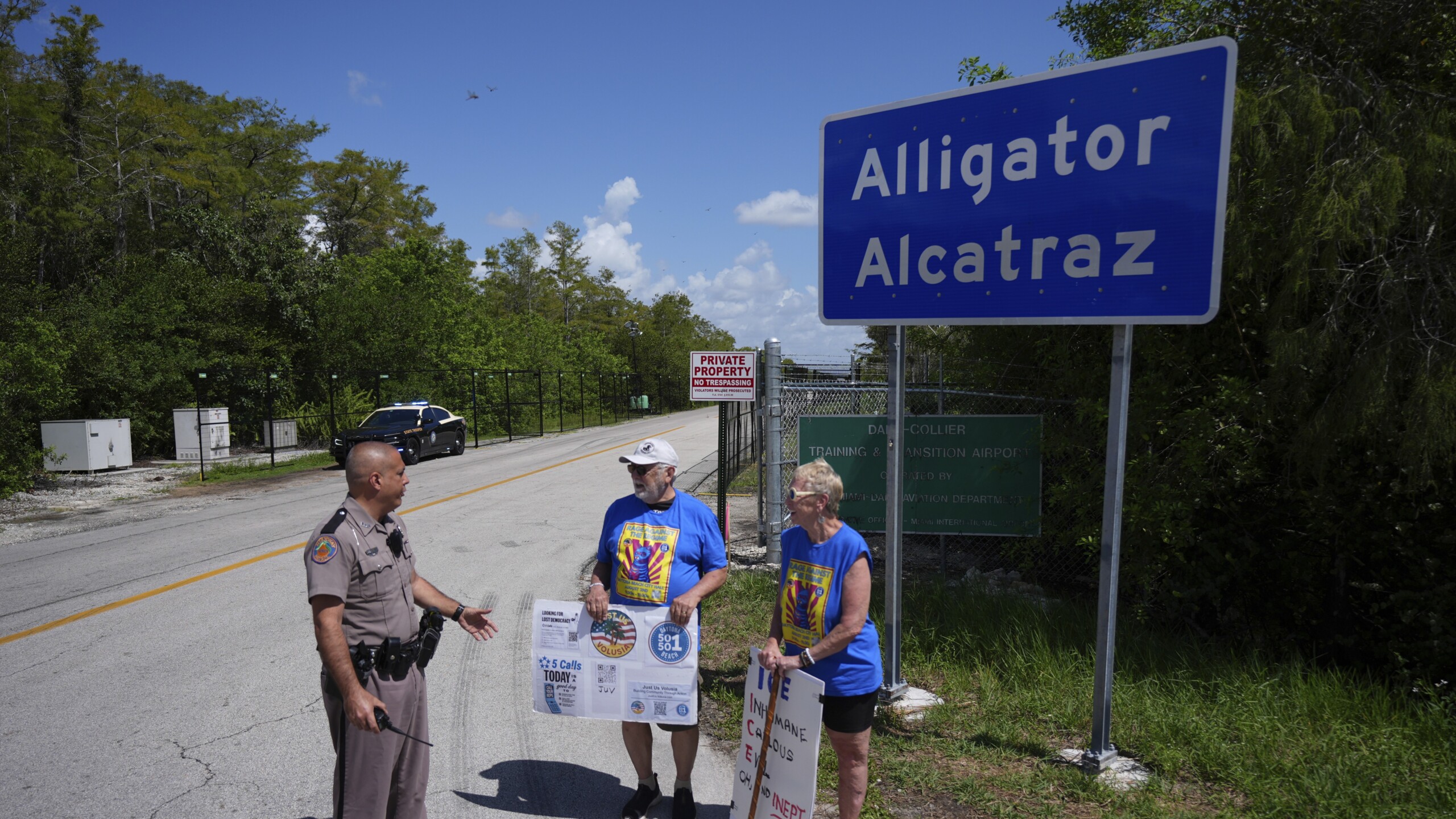 Protesters with police officer outside Alligator Alcatraz