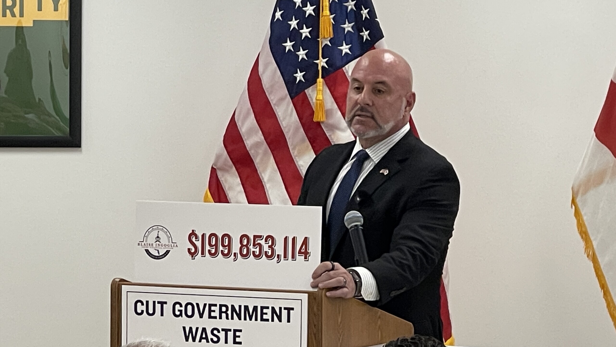 Florida's chief financial officer, Blaise Ingoglia, stands at a lectern during a Florida DOGE news conference in Jacksonville.