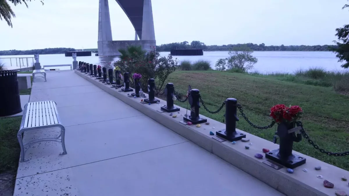 A line of 33 memorial markers shaped like dock cleats, each with a nameplate and a photo of a crew member on the El Faro.
