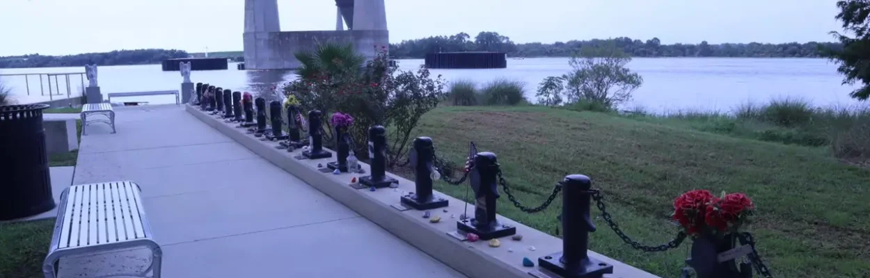 A line of 33 memorial markers shaped like dock cleats, each with a nameplate and a photo of a crew member on the El Faro.