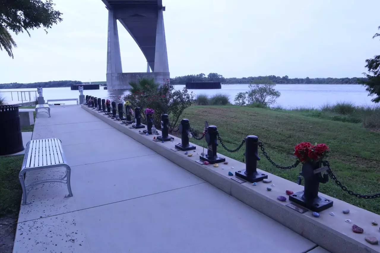 A line of 33 memorial markers shaped like dock cleats, each with a nameplate and a photo of a crew member on the El Faro.