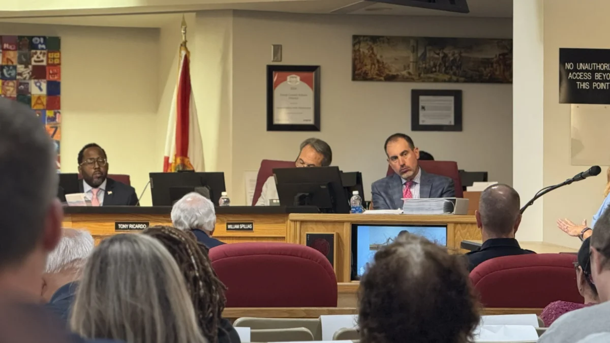 School Board lawyer sits on the dais and listens to public commenter speak