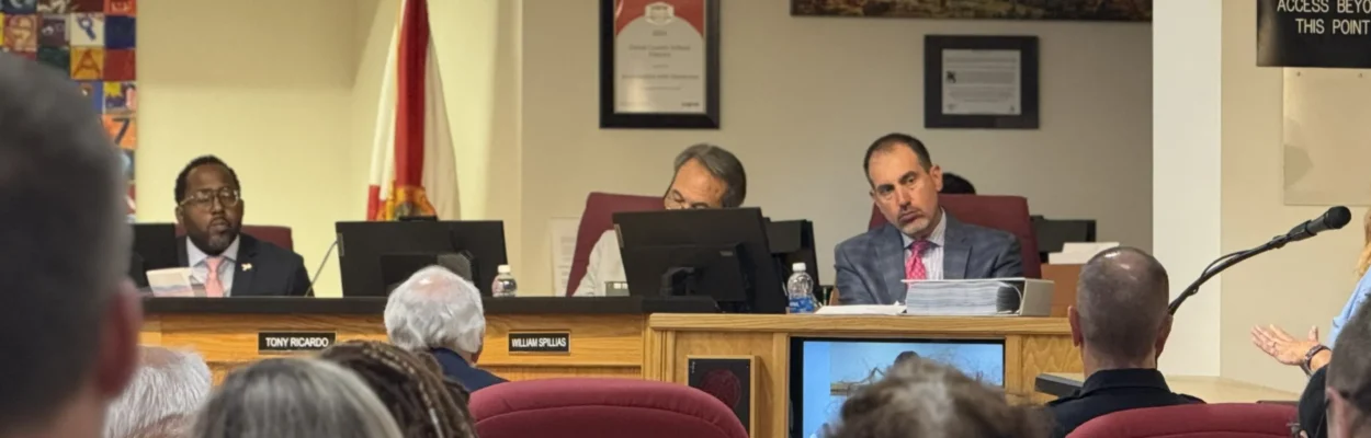 School Board lawyer sits on the dais and listens to public commenter speak