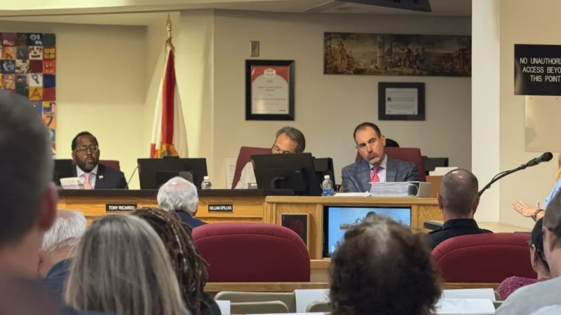 School Board lawyer sits on the dais and listens to public commenter speak