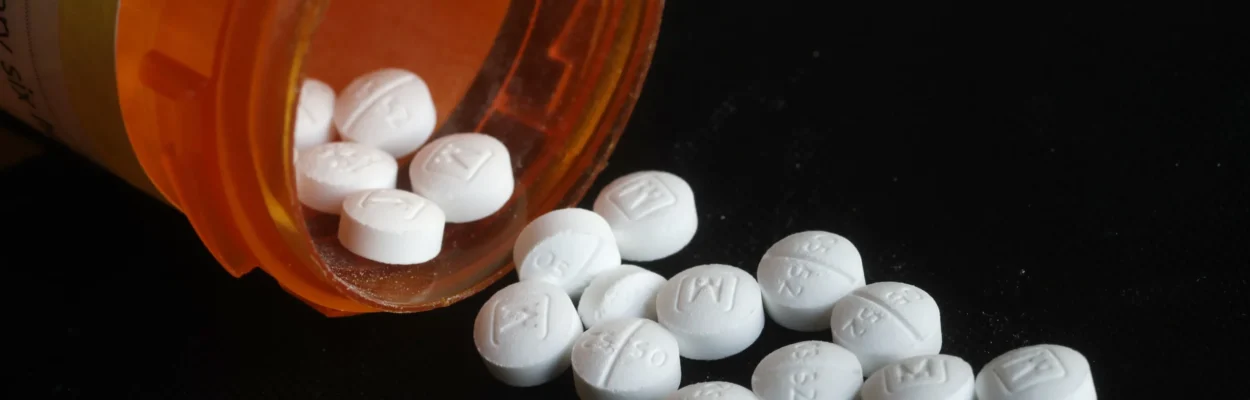 Oxycodone drug pills spill out of a bottle.