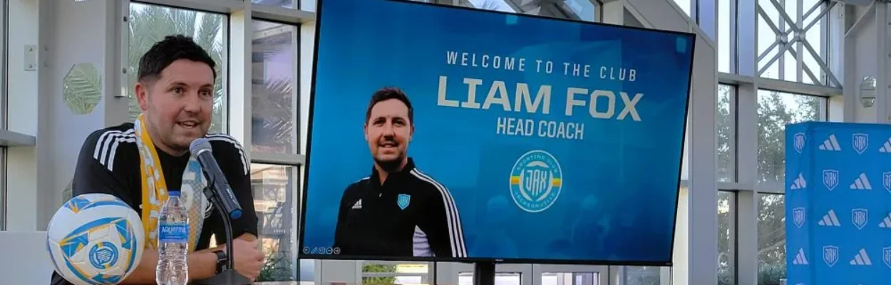 Sporting Jax’s first men’s head coach, Liam Fox, speaks at a microphone.
