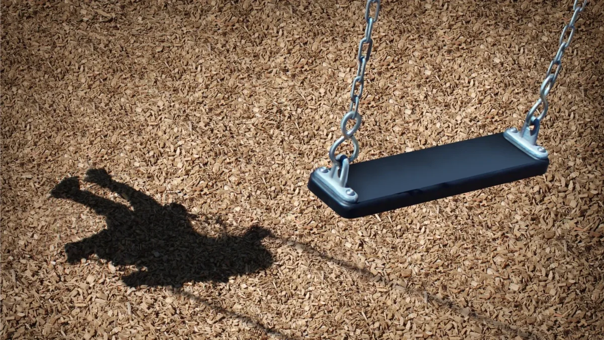 A child's shadow and an empty playground swing symbolize missing or endangered children.