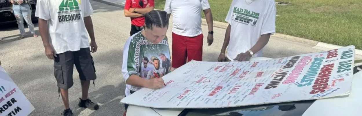 People sign a MAD DADS poster remembering murder victims in late 2024.