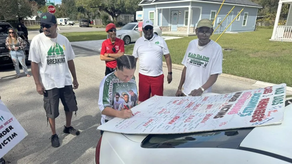 People sign a MAD DADS poster remembering murder victims in late 2024.
