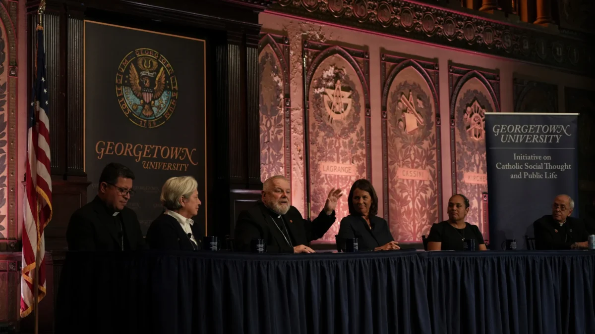 The archbishop of Miami, Thomas Wenski, raises his hand while addressing a crowd during a panel on immigration at Georgetown University in Washington.