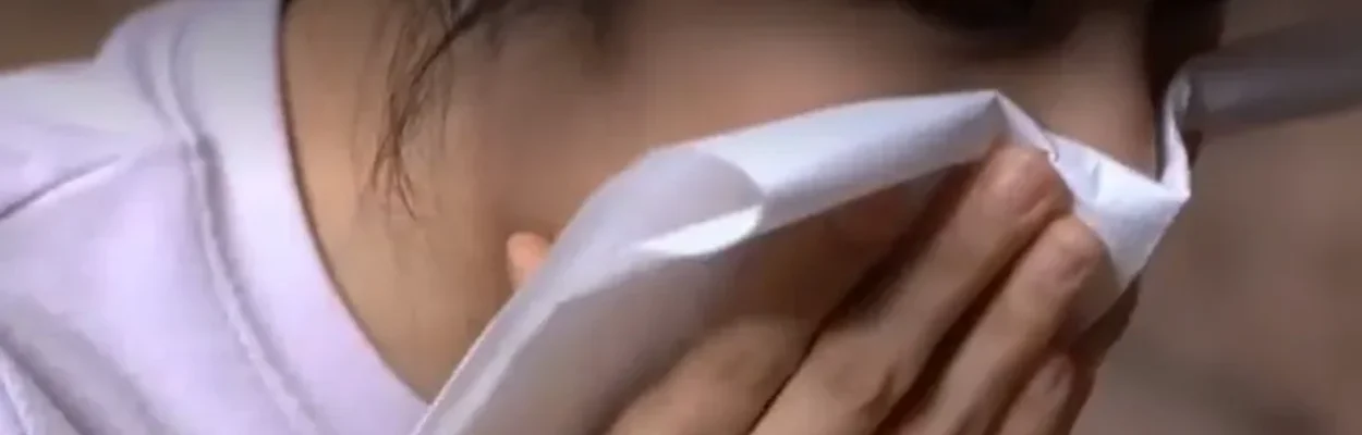 A flu patient coughs into a tissue