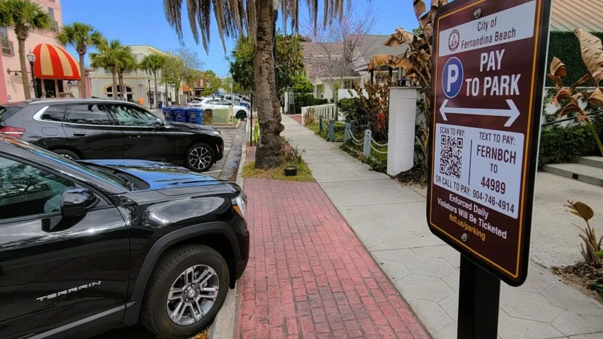 Cars parked in Fernandina Beach with paid parking signs nearby.