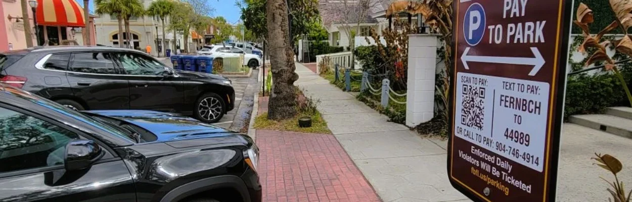 Cars parked in Fernandina Beach with paid parking signs nearby.