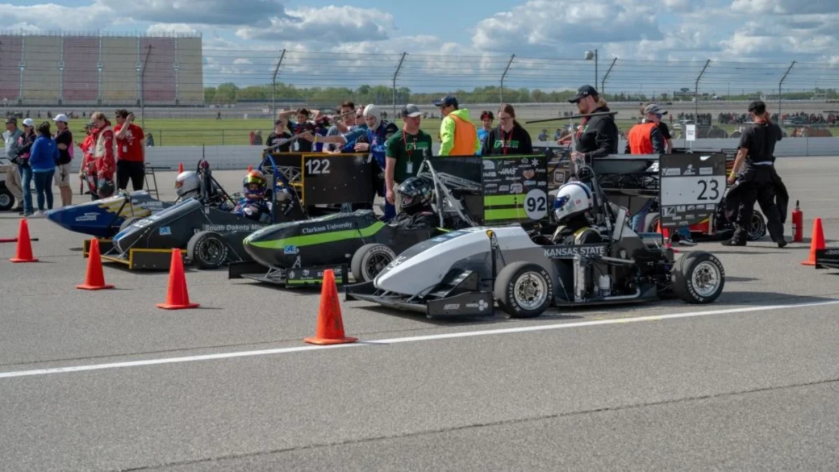 Singe-seat race cars line up on a track.