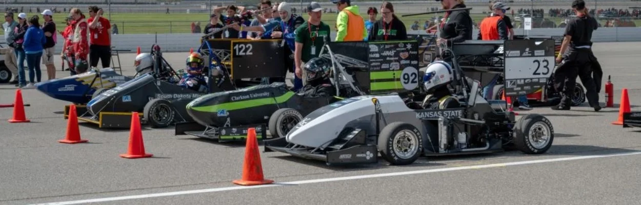 Singe-seat race cars line up on a track.