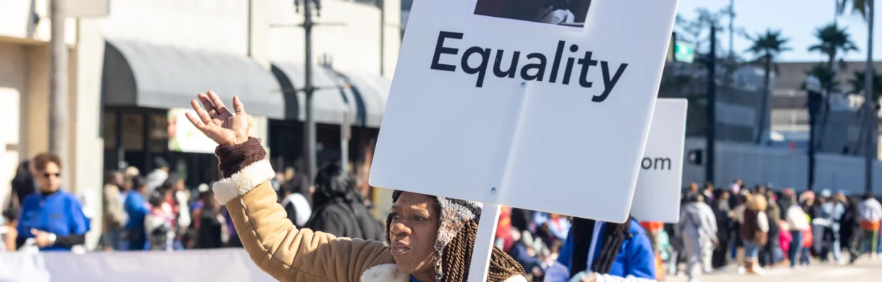 Debra Joshua shares a DEI sentiment while participating in the Martin Luther King Jr. Grand Parade.