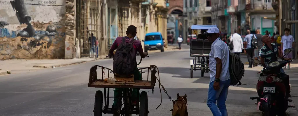 A man rides a tricycle with his leashed dog running alongside him during a blackout in Havana, Cuba, Monday, March 16, 2026.
