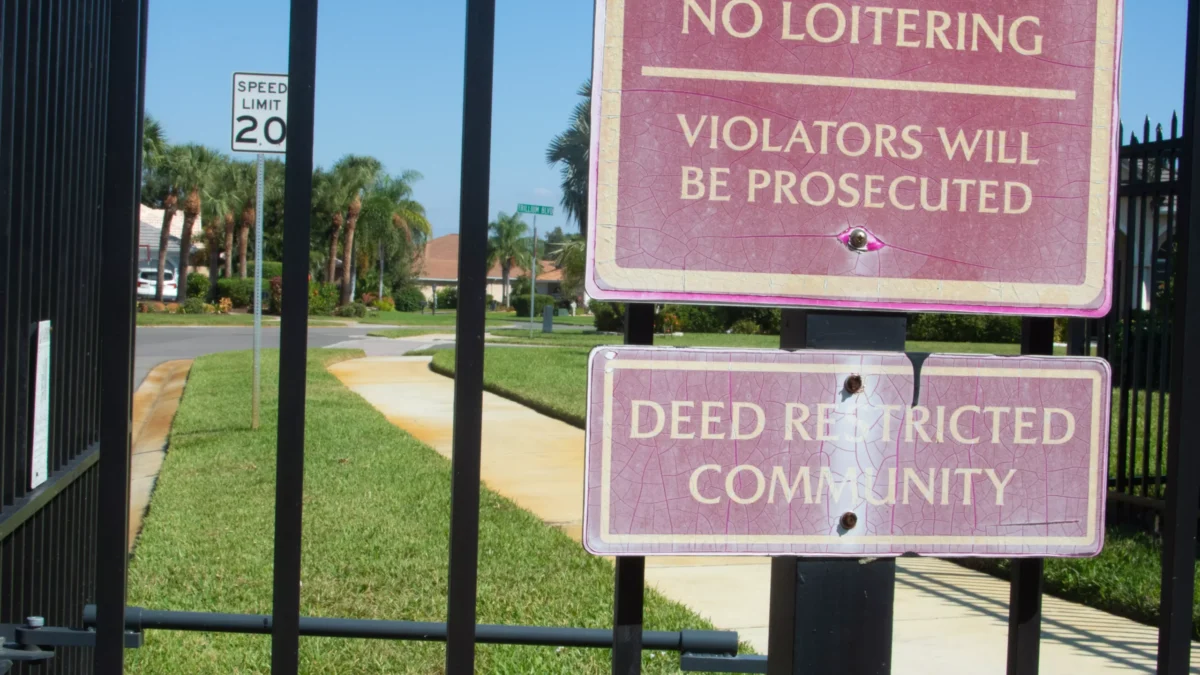 A gate with a sign in front of a neighborhood with a homeowners association.