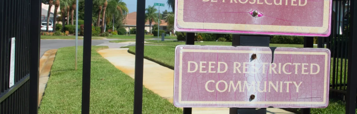 A gate with a sign in front of a neighborhood with a homeowners association.