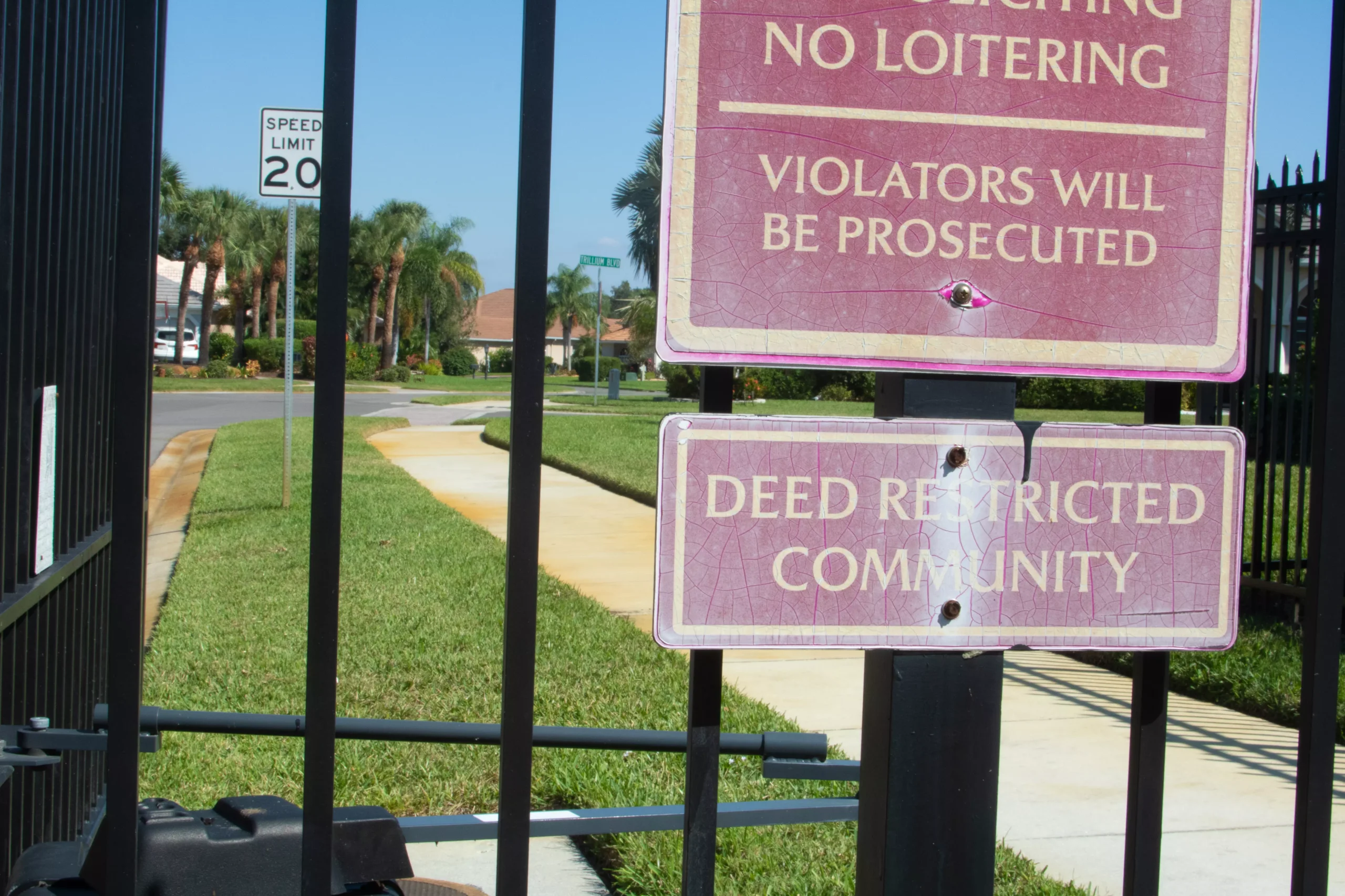 A gate with a sign in front of a neighborhood with a homeowners association.