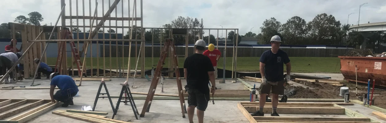 Volunteers work on laying a home's foundation and putting up walls.